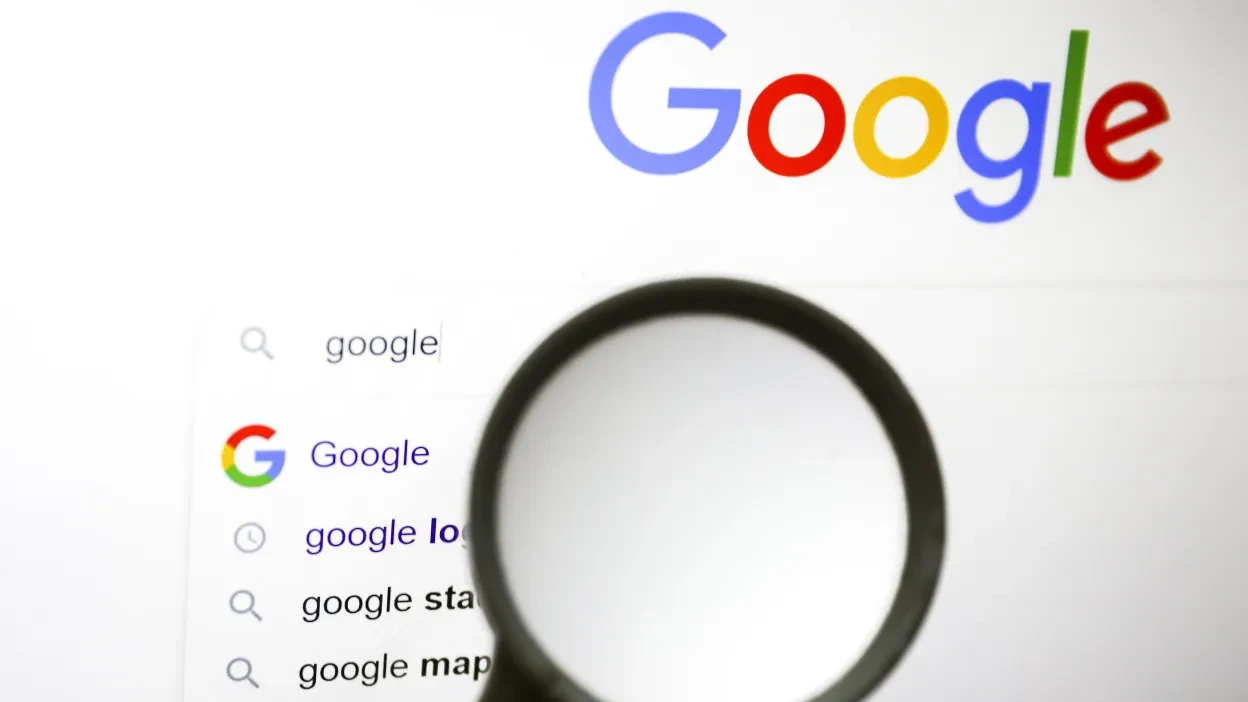The Google logo above a search box, viewed through a magnifying glass.