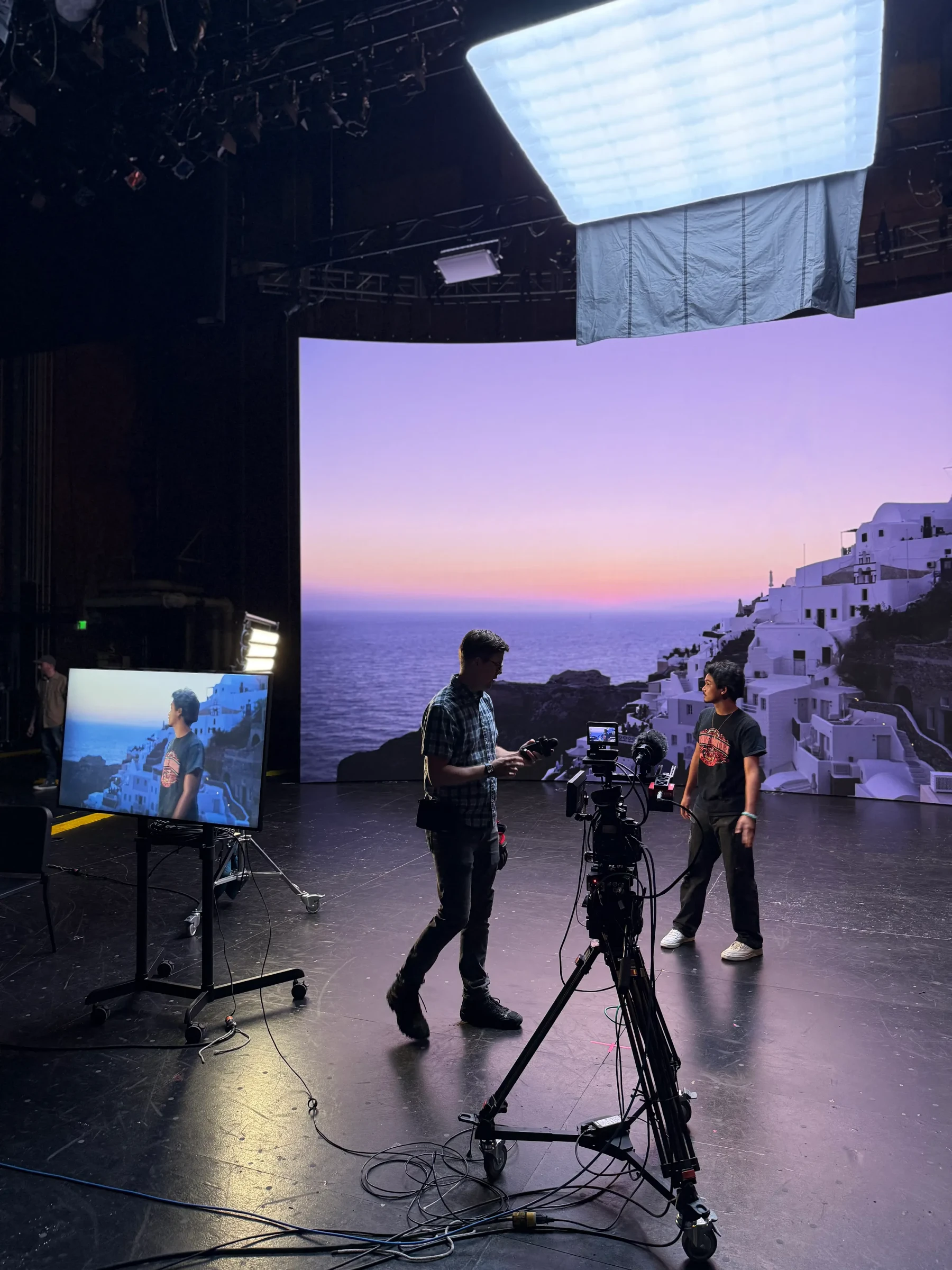 A camera crew working in front of a large virtual-production screen.