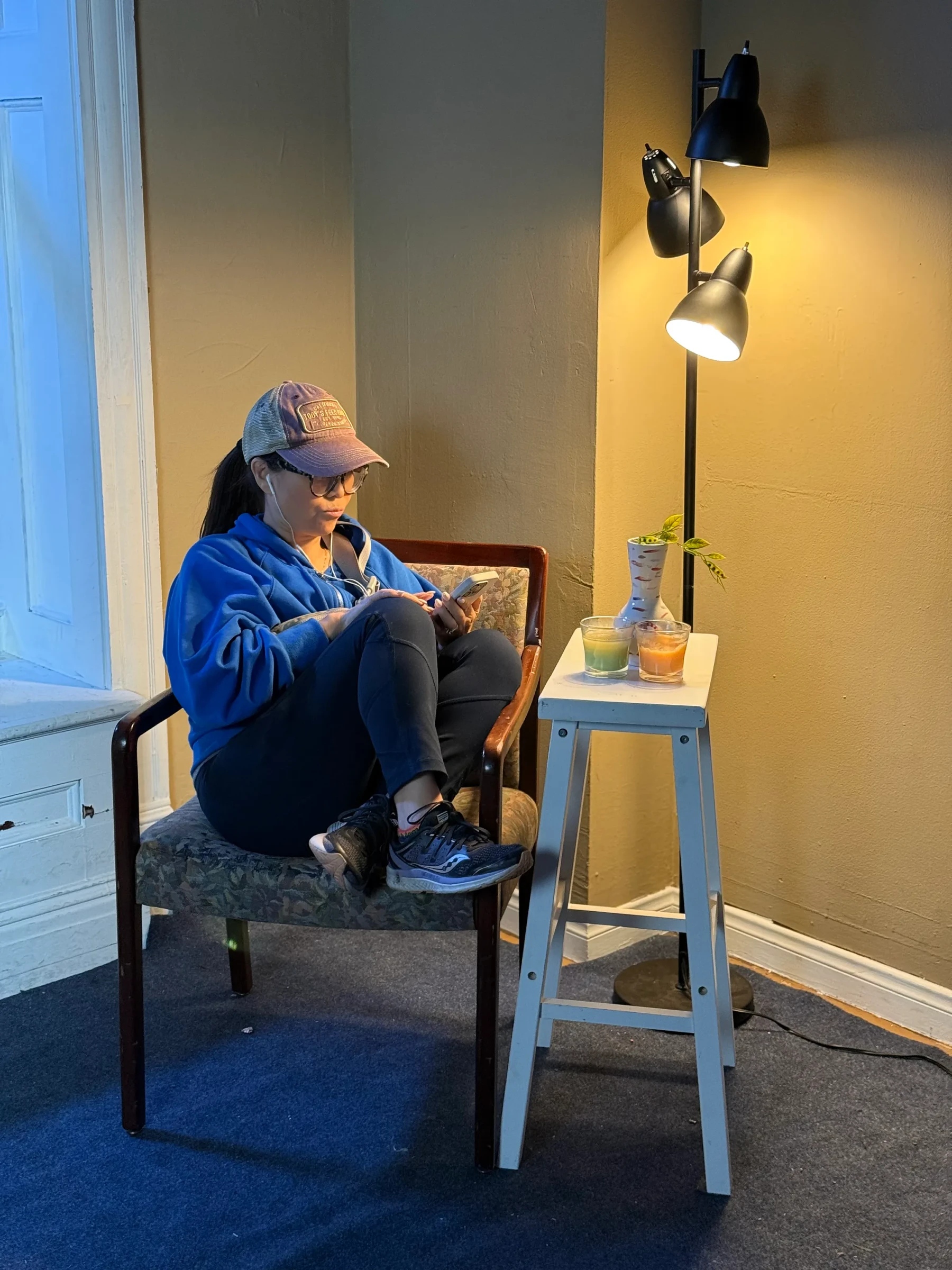 An actor seated beneath a lamp during a filmed scene.