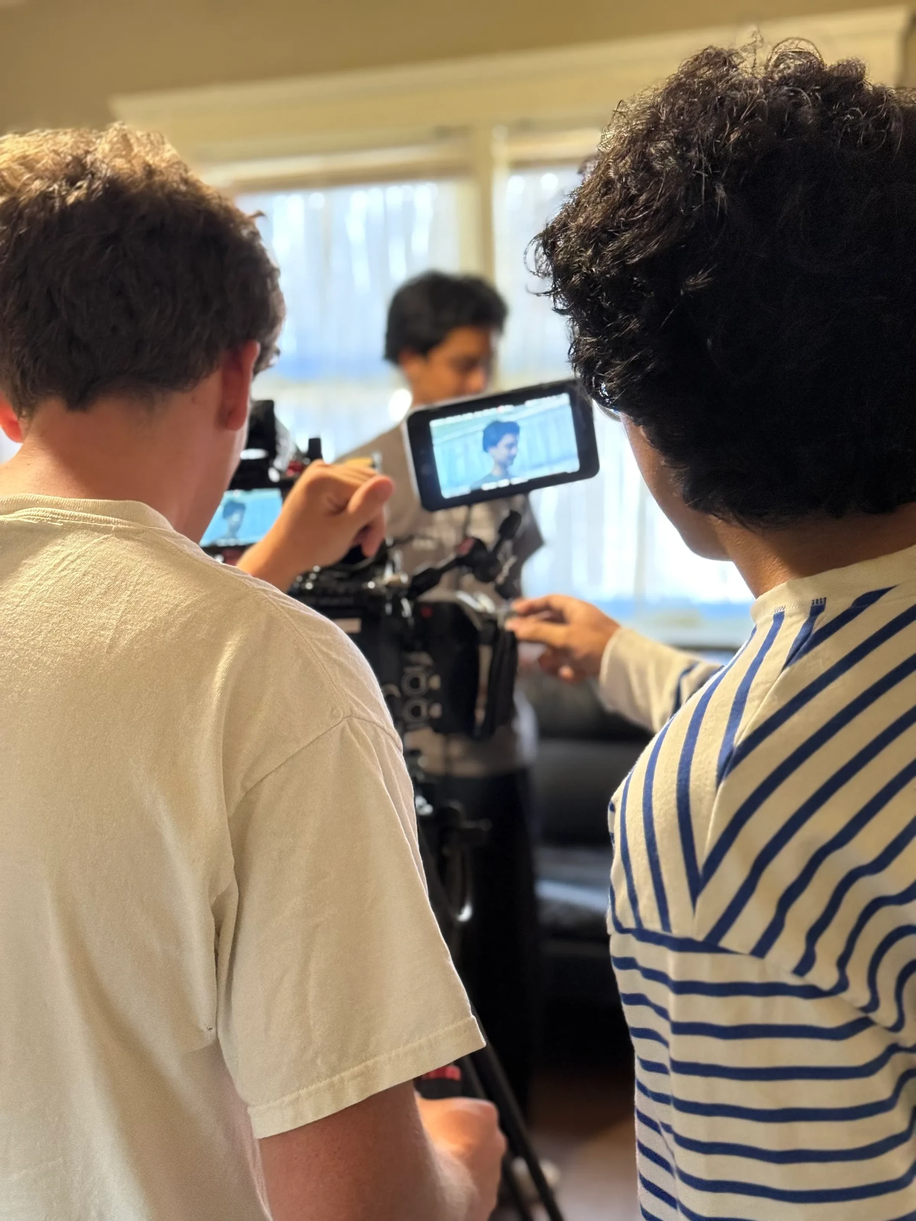 Crew members watching a camera monitor while filming indoors.
