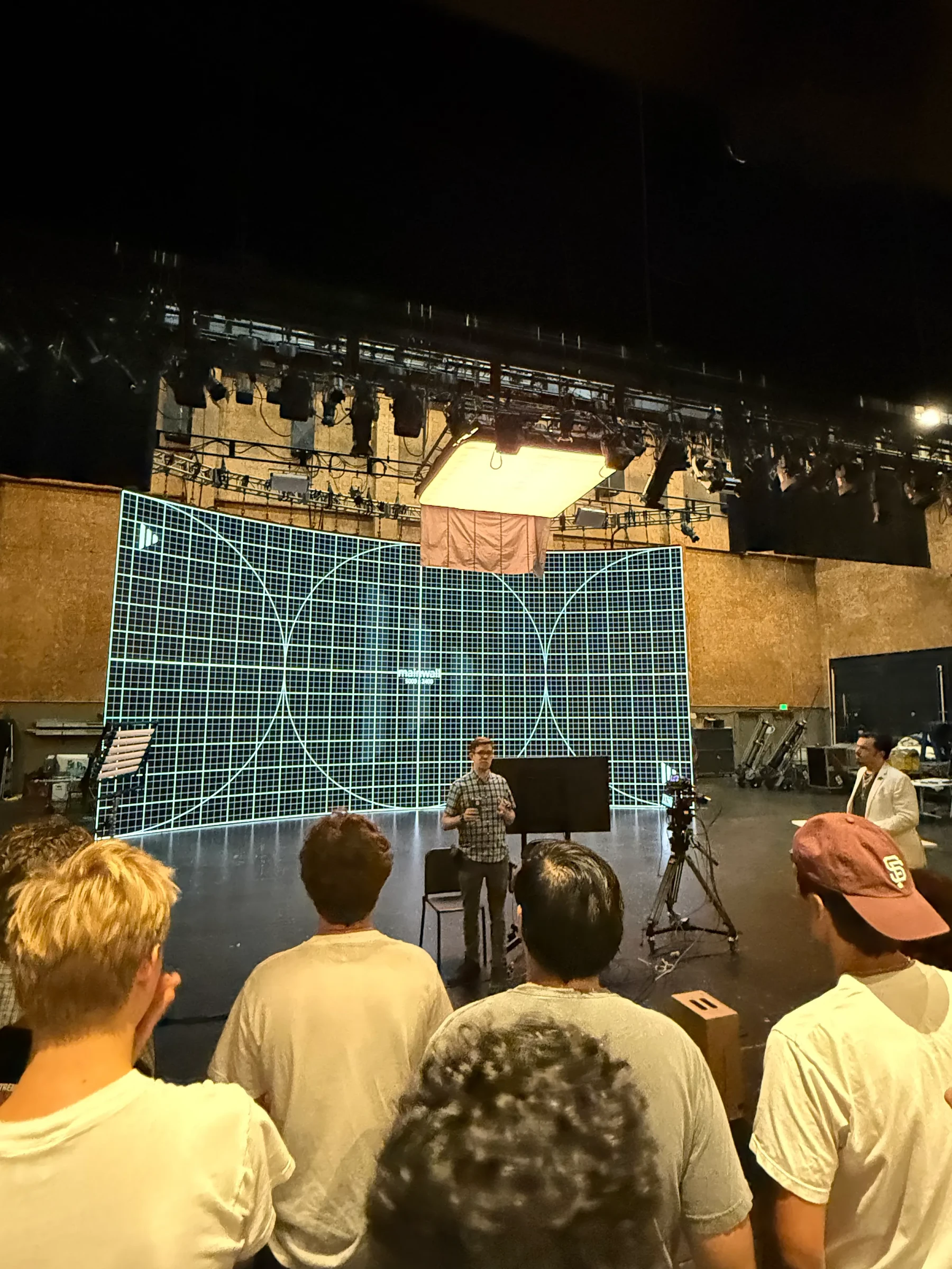 A group watching a demonstration on a large studio stage.