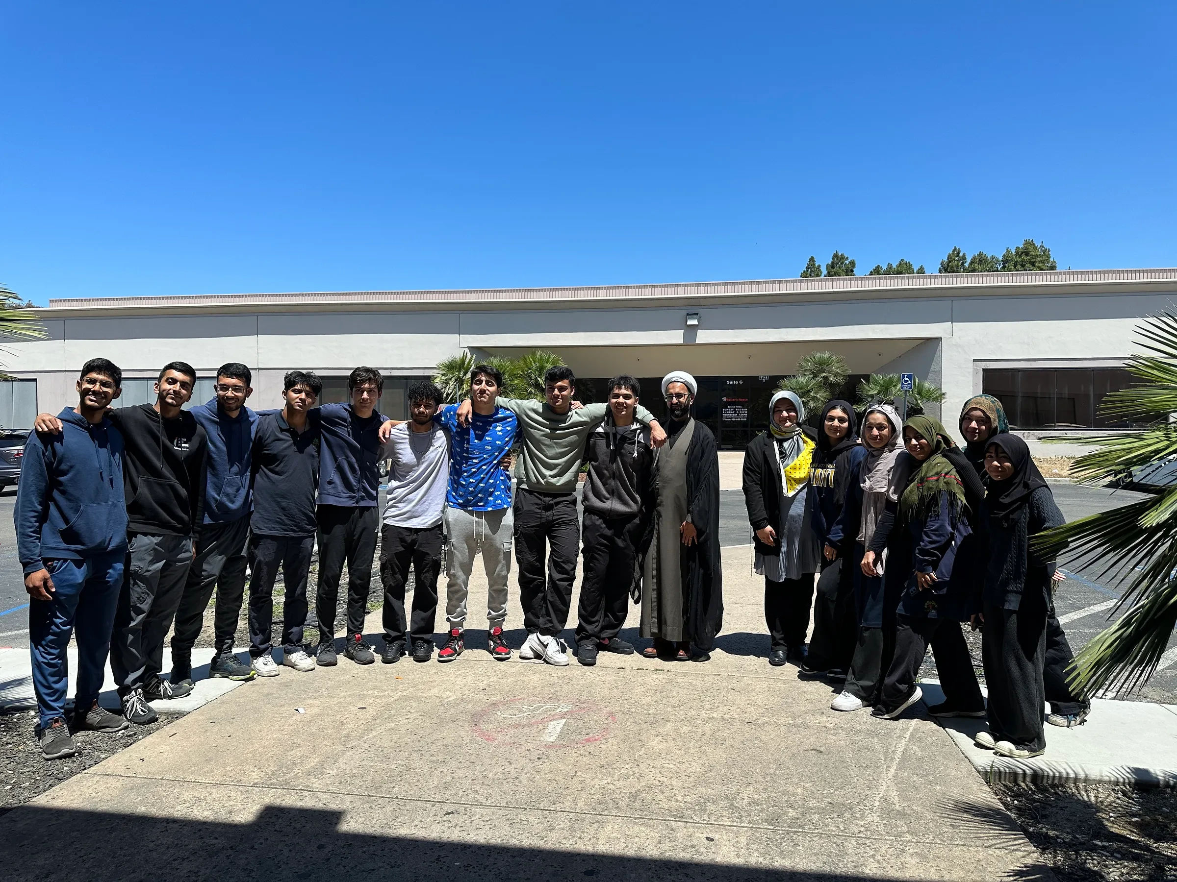 A group posing outdoors beside a school building.