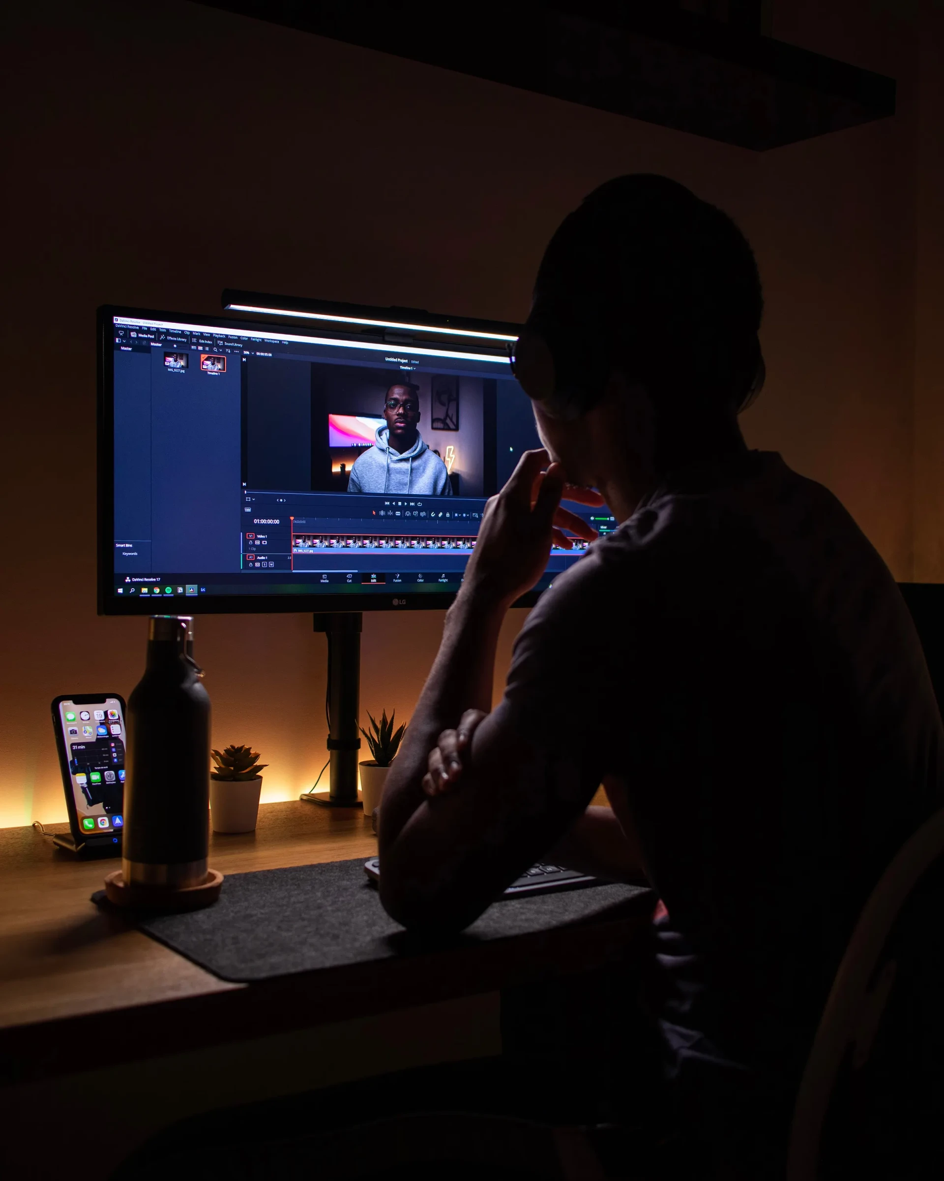 A person working at a video-editing computer in a dimly lit room.