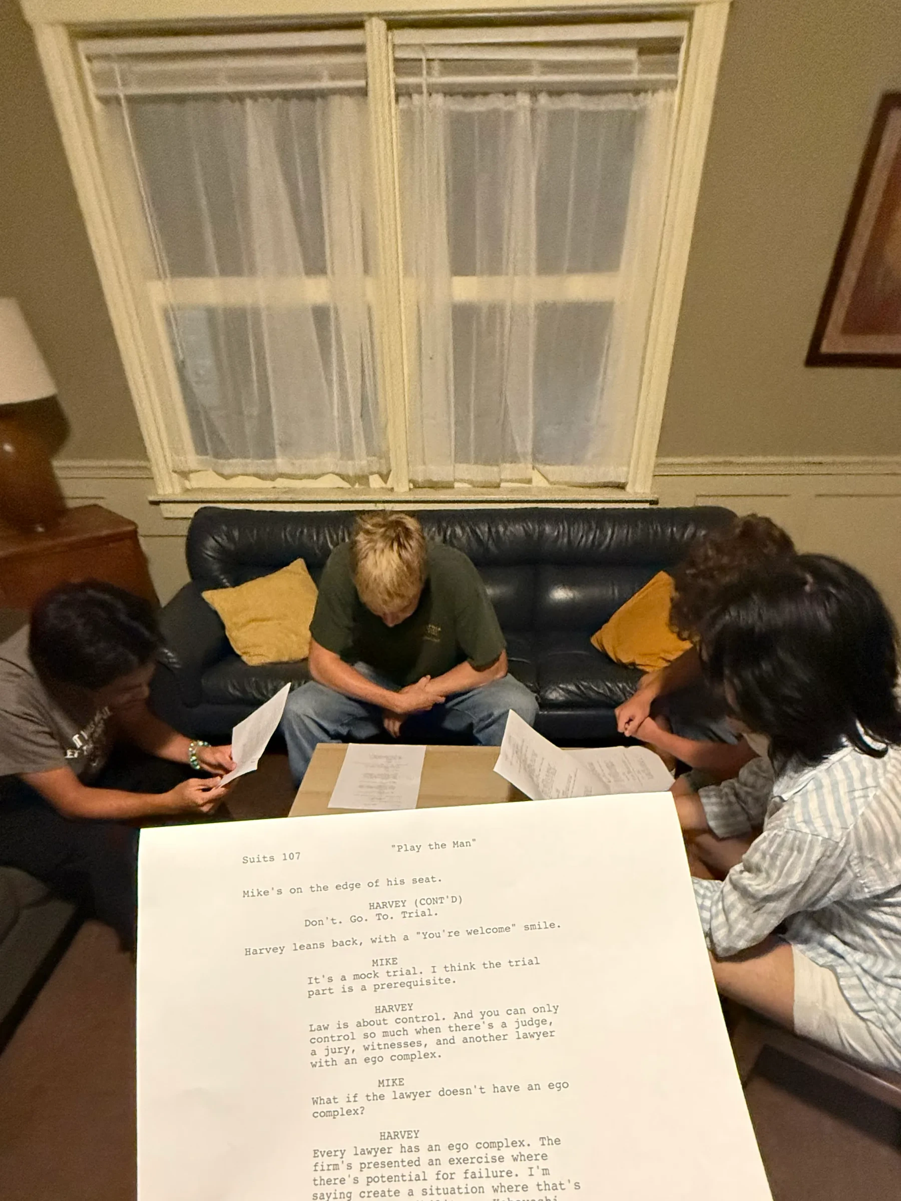 A script page held in front of a group rehearsing at a table.