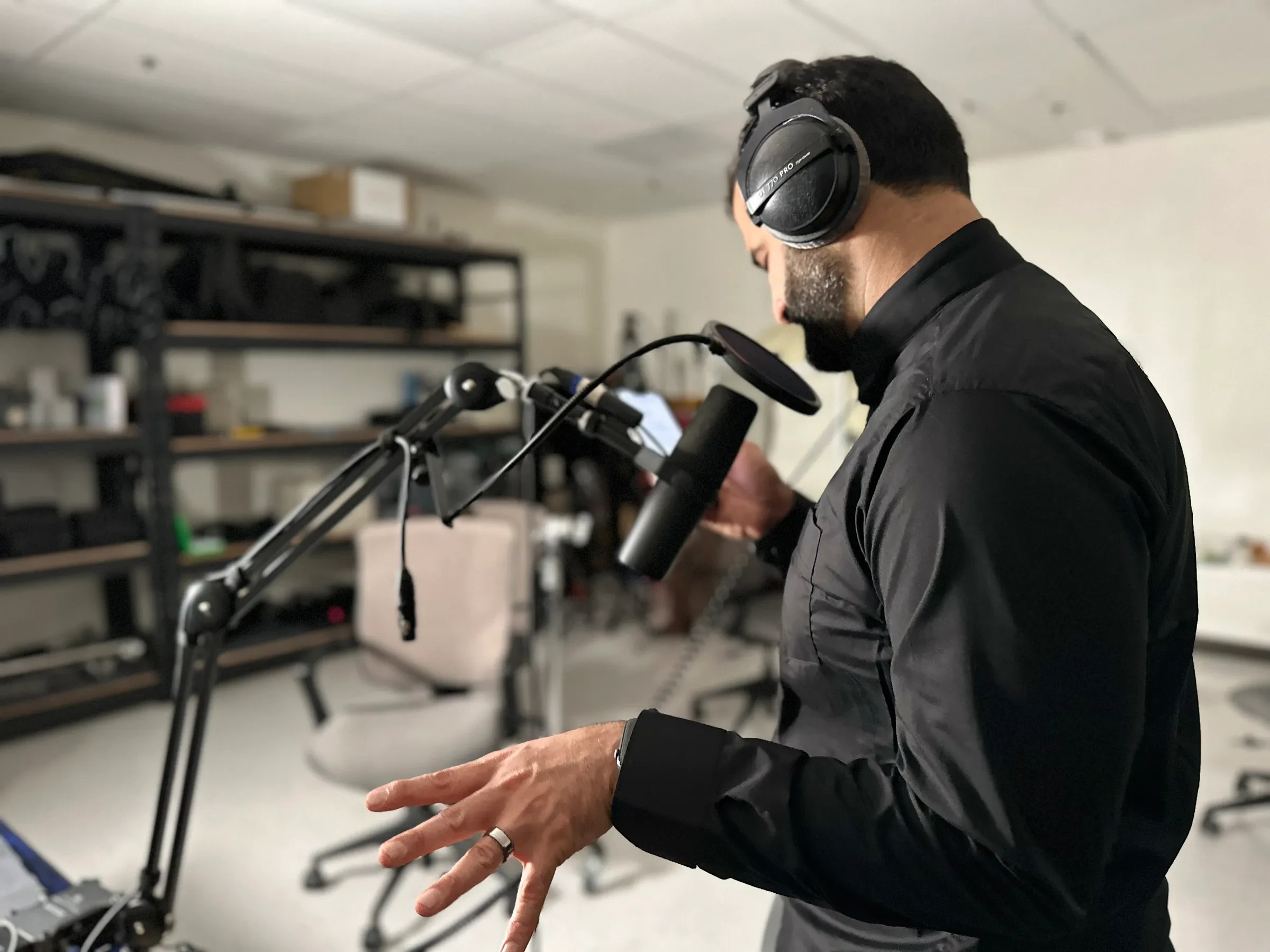 A person wearing headphones and speaking into a studio microphone.