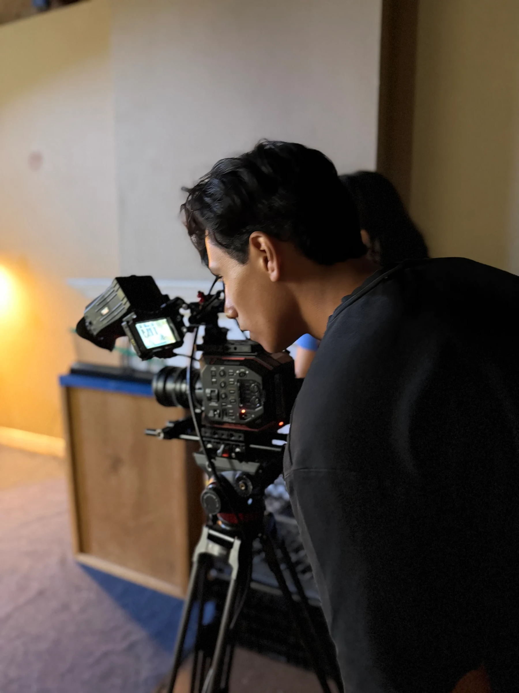 A camera operator framing a shot of a seated actor.