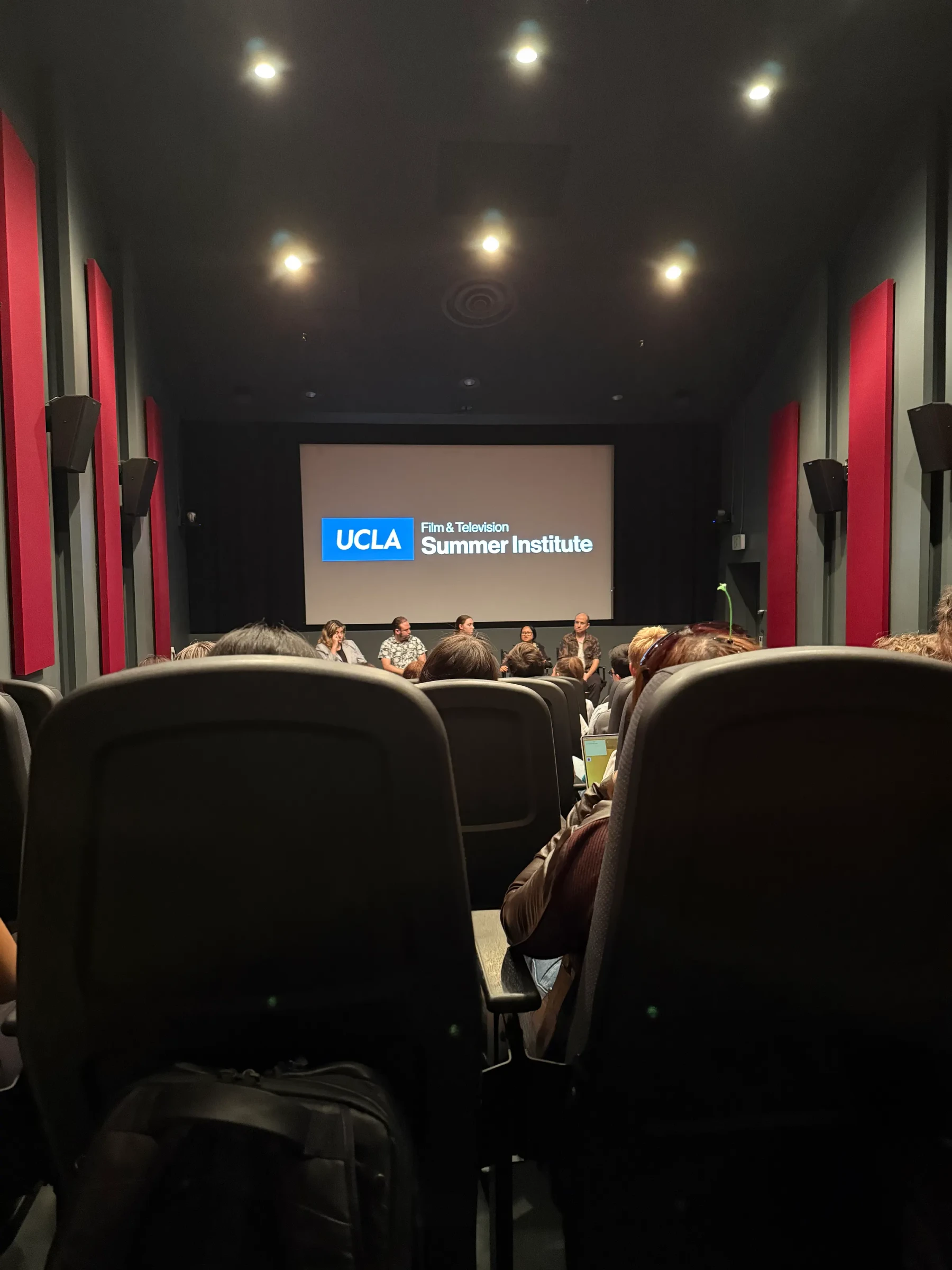 A screening room with red curtains and a presentation on the screen.