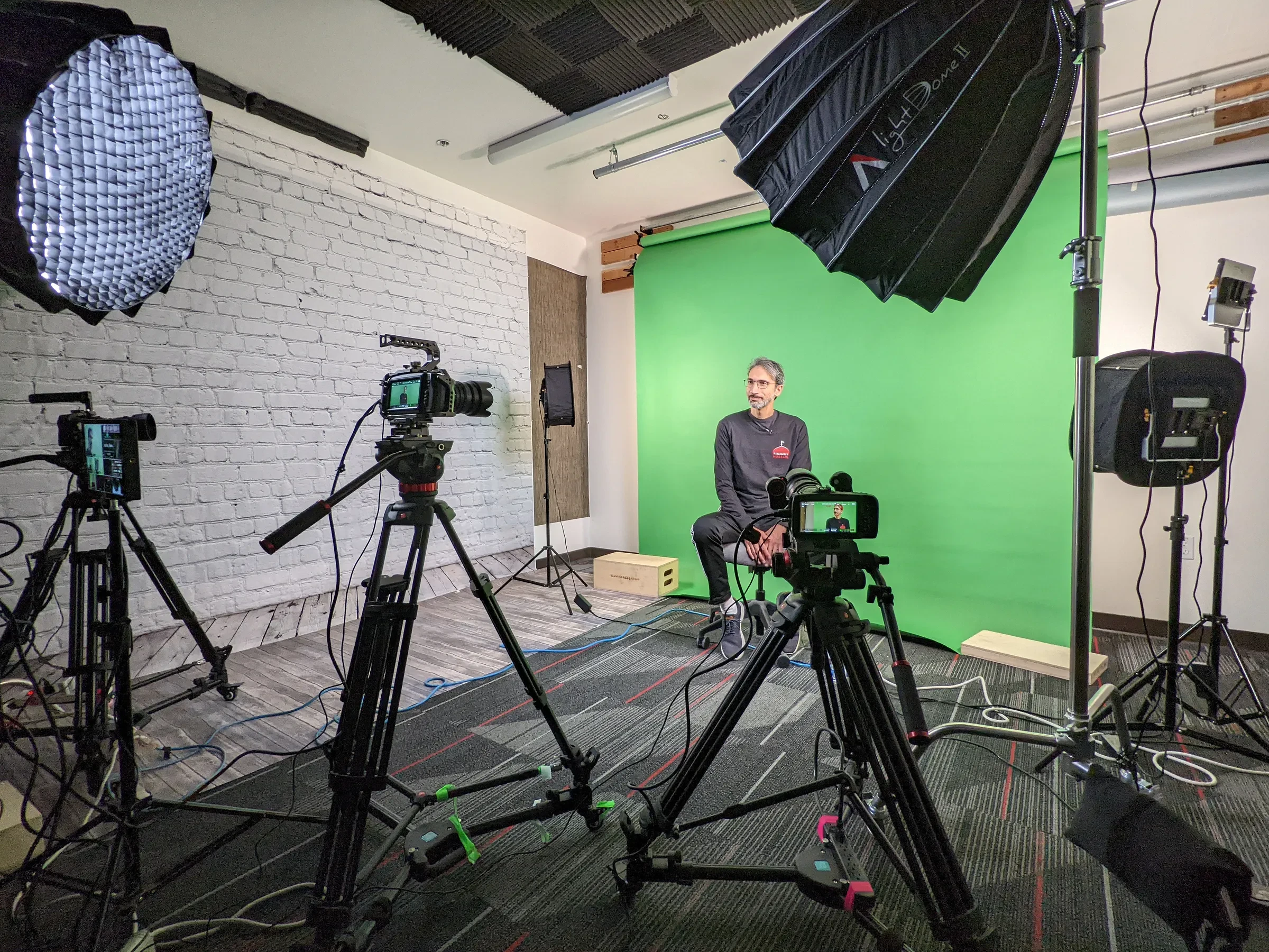 A studio camera setup filming a person in front of a green screen.