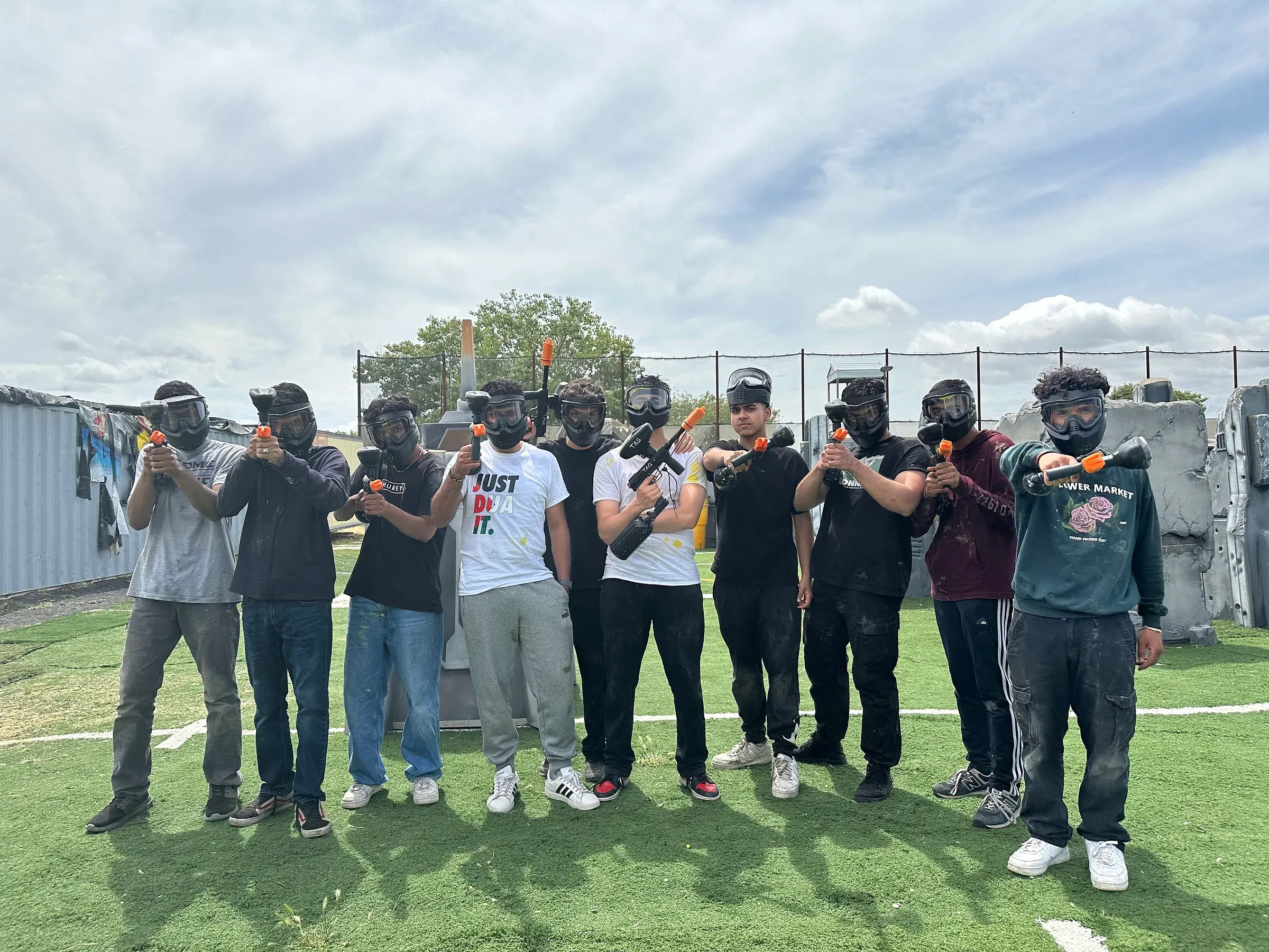 A group posing together at an outdoor paintball venue.