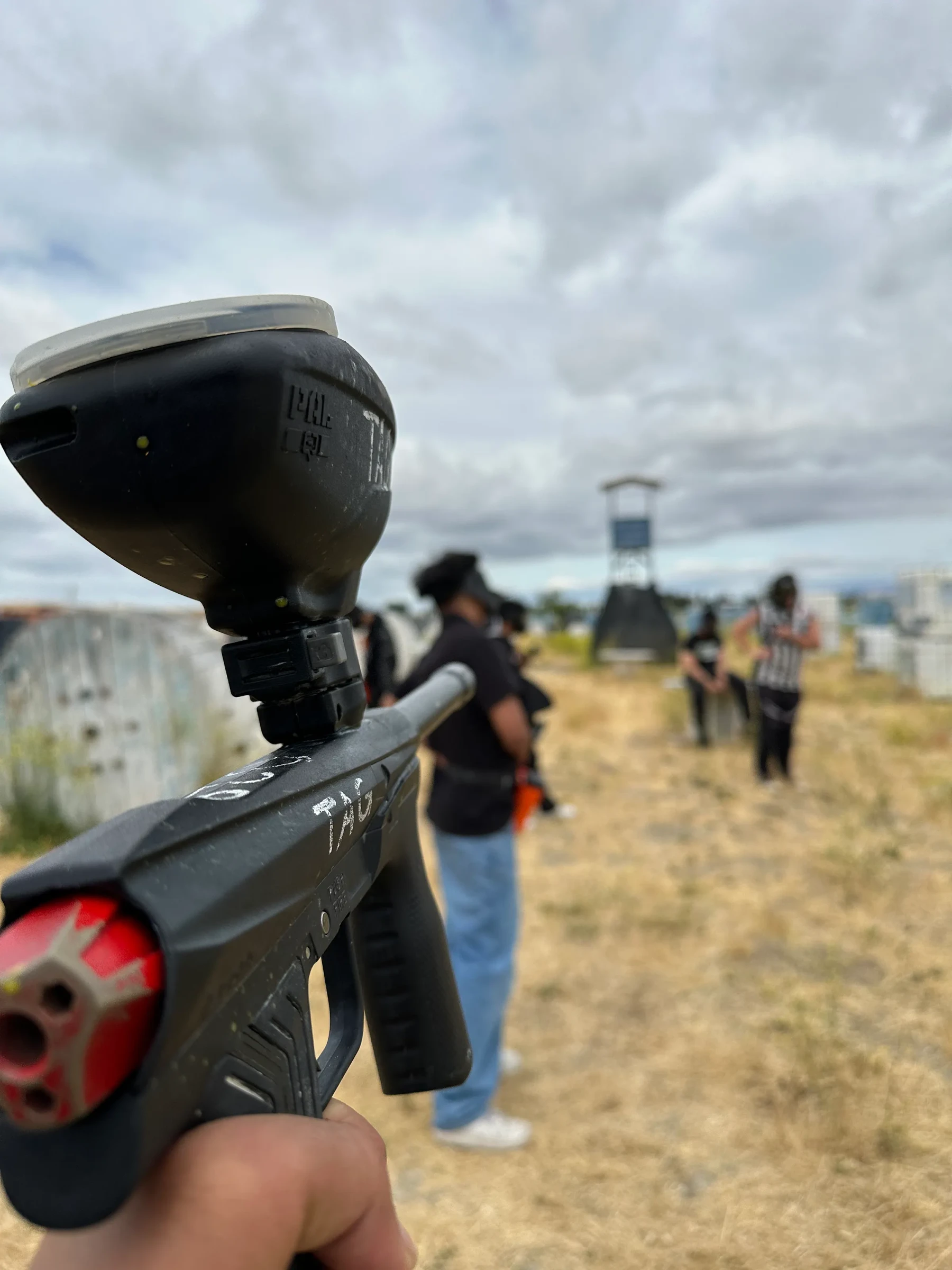 A first-person view of a paintball marker pointed down an outdoor playing field.